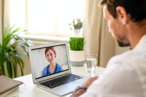 Man having video call with doctor on laptop at home, online consultation concept